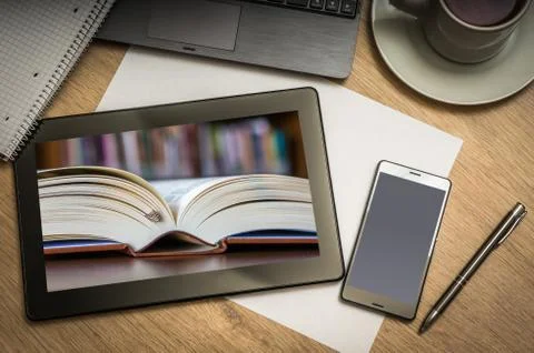 Digital tablet on business table with open book in library on screen and mobi Foto stock
