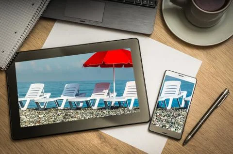 Digital tablet on business table with sunbathing beds and red umbrella on scr Stock Photos