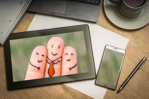 Digital tablet on business table with three happy fingers on screen and mobil Stock Photos