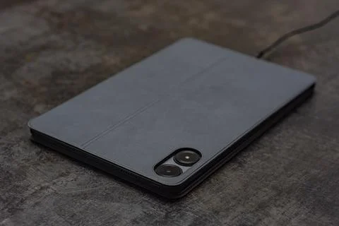 Digital tablet charges on the concrete table with a cable. Concept for char.. Stock Photos