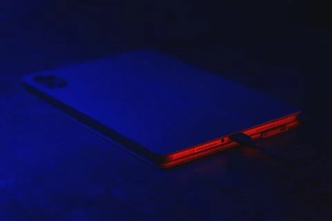 Digital tablet charges on the concrete table with a cable with technology l.. Stock Photos