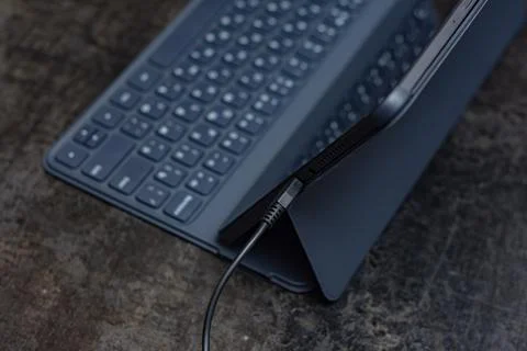Digital tablet charges on the concrete table with a cable. Concept for chargi Stock Photos