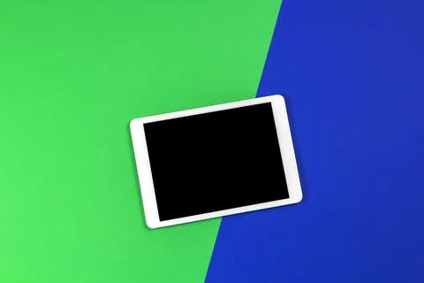 Digital tablet computer on light green and blue background. Top view Stock Photos