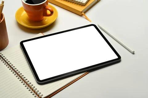 Digital tablet with empty screen, coffee cup and notebook on white office desk Foto stock