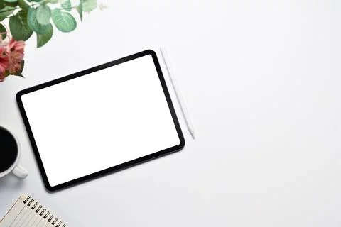 Digital tablet with empty screen, coffee cup and notepad on white table. Top Stock Photos