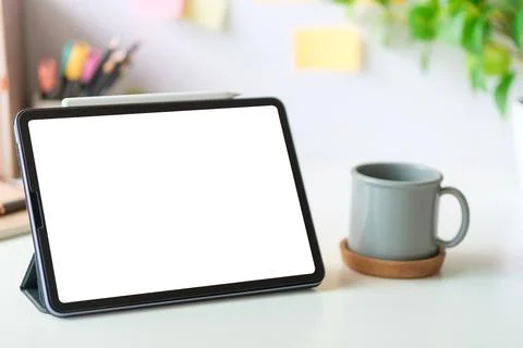 Digital tablet with empty screen on coffee cup and notepad on white office .. Stock Photos