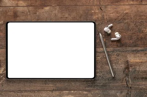 Digital tablet with empty white screen, stylus pen, wireless earphones on woo Stock Photos