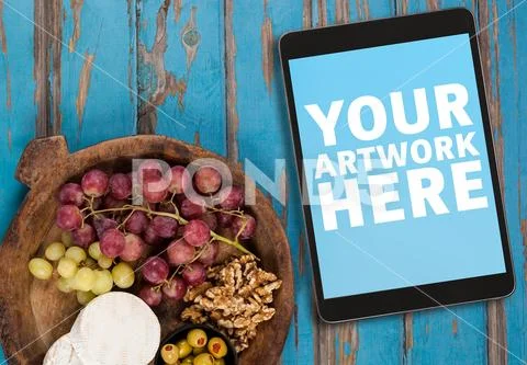 Digital tablet with fruit on wooden plank PSD Template