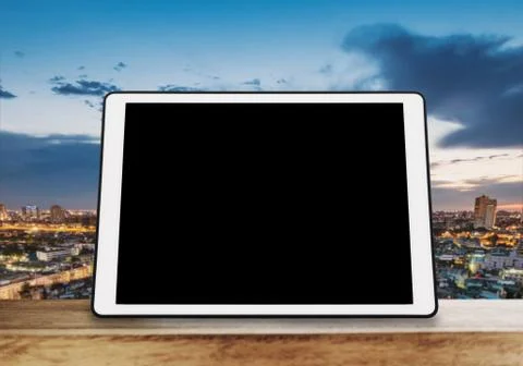 Digital tablet, isolated black screen on wooden table with blur city skyline Stock Photos