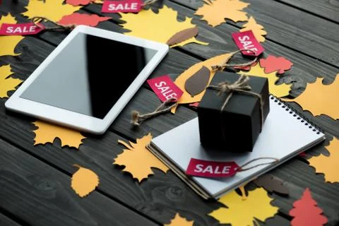 Digital tablet, notepad and little gift box on wooden tabletop with foliage Stock-Fotos