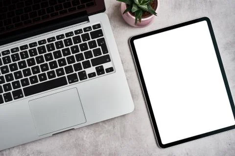 Digital tablet with open laptop on grey concrete background. Stock Photos