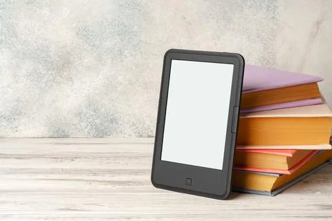 Digital tablet with a stack of books on gray background Foto stock