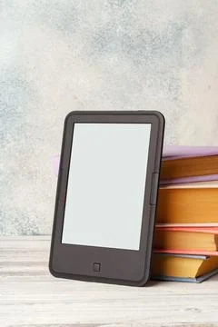 Digital tablet with a stack of books on gray background Stock Photos