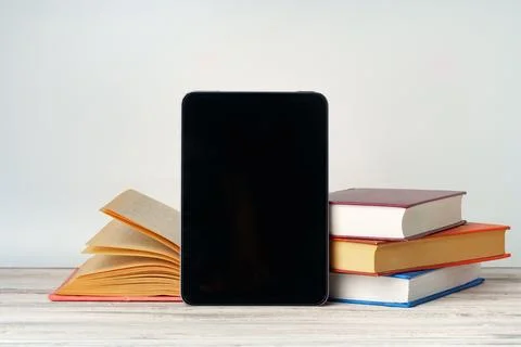 Digital tablet with a stack of books on gray background 写真素材