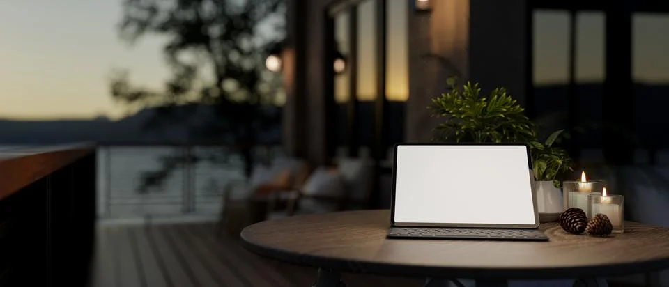 A digital tablet on a table on a home balcony with a nature view at dusk. Stock Illustration