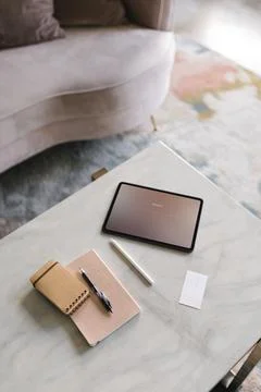 Digital tablet on a white marble table in a living room Stock Photos