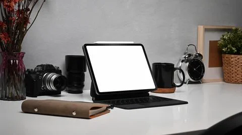 Digital tablet with wireless keyboard, camera and supplies on white table. Empty Foto stock