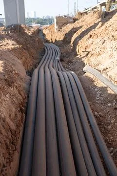 Digital telecommunication network pipes hold cables buried underground. Man.. Stock Photos