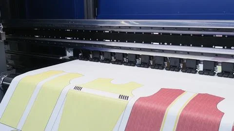 A digital textile printer in printing colorful shirt patterns directly onto.. Stock Photos