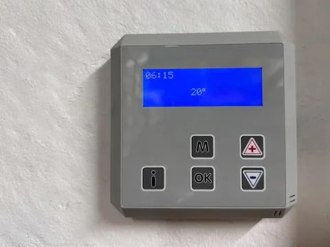 Digital thermostat control panel with blue display showing time and tempera.. Stock Photos