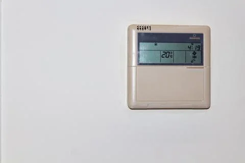 Digital thermostat control panel mounted on a white wall for indoor temperature 스톡 사진