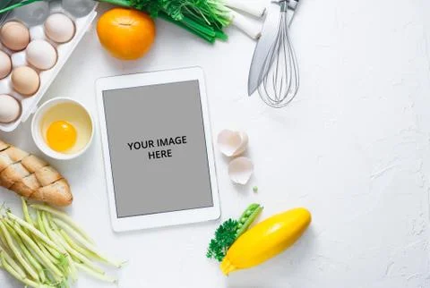 Digital touch screen tablet with fresh vegetables and kitchen utensils on Stock Photos