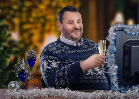 Digital yuletide joy: Gent in patterned sweater toasts unseen friends. Foto stock