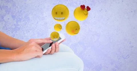 Digitally generated image of emojis flying over hands using smart phone Stock Photos
