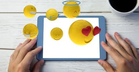 Digitally generated image of emojis flying over hand using tablet computer by Stock Photos