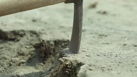 Digs the ground with a tool 2 Stock Footage 323791835