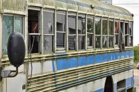 Dilapidated and rusty bus with broken windows in a remote area. Scrap. Stock Photos