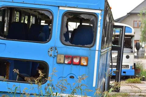 Dilapidated and rusty bus with broken windows in a remote area. Scrap. Stock Photos