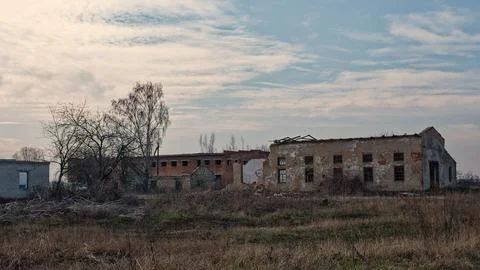 A dilapidated building with broken windows under a cloudy sky. Fotos de archivo