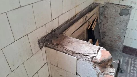 Dilapidated building interior featuring cracked ceramic tiles and rough concrete Stock Photos