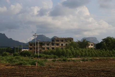 A dilapidated building surrounded by fields, with mountains in the backgrou.. Stock Photos