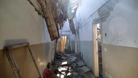 A dilapidated hallway with a collapsed ceiling and debris scattered on the .. Stock Photos