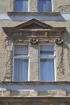 Dilapidated historic window with a triangular pediment and exposed bricks Stock Photos