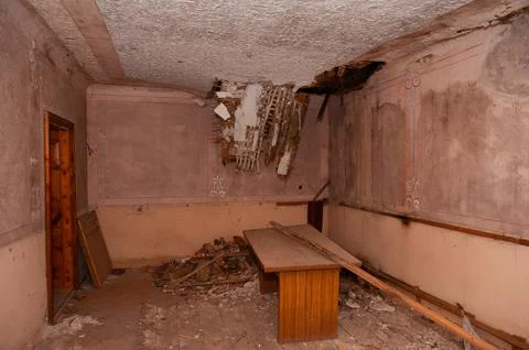 Dilapidated Room With Collapsed Ceiling Showing Exposed Beams And Debris Am.. Stock Photos