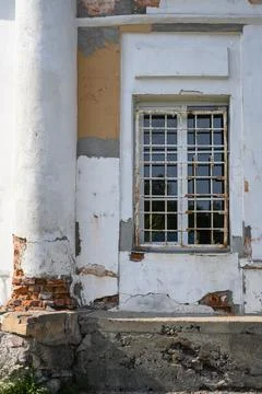 A dilapidated wall with a window and a column of a medieval church Stock Photos