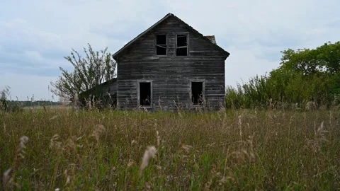 A dilapidated wooden farmhouse with missing windows is set in autumn grass Stock Footage 285553293