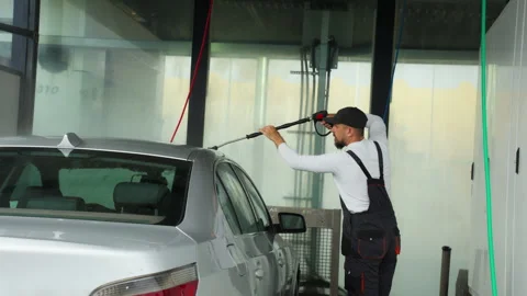 Diligent car wash worker in uniform thoroughly cleaning silver automobile w.. Stock Footage 320890252