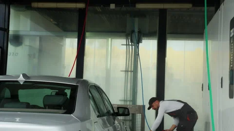 Diligent car wash worker in uniform thoroughly cleaning silver sedan with h.. Video stock 320890477