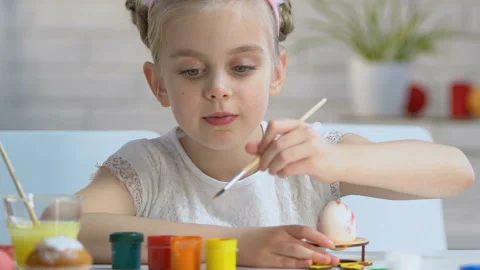 Diligent girl carefully putting pattern with paints on egg, Easter decoration Stock Footage 99722294