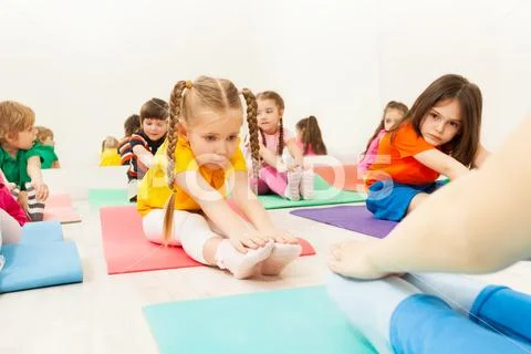 Diligent girl doing stretching exercise on mat Stock Photos