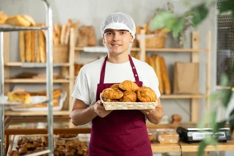 Diligent guy baker offers to buy fresh delicious croissants Photos