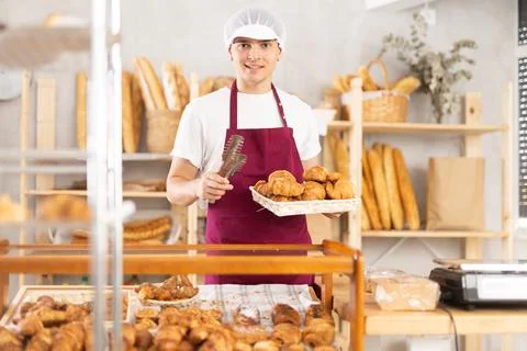 Diligent guy baker offers to buy fresh delicious croissants Photos