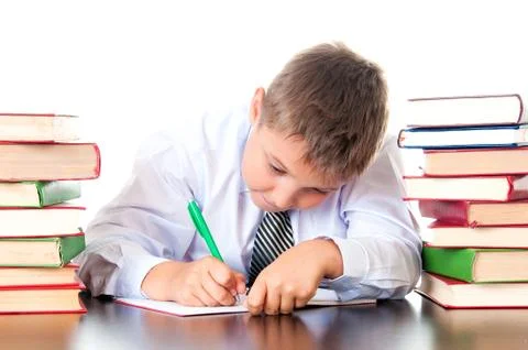 A diligent high school student boy sits in a library with books and learns le Stock Photos