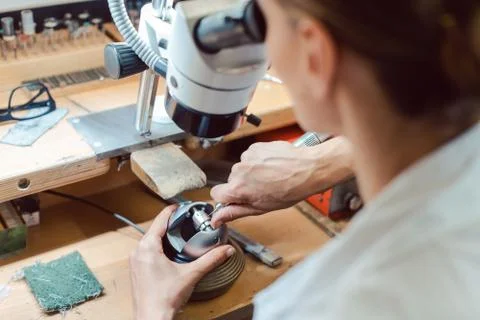 Diligent jeweler working on microscope at her workbench Stock Photos