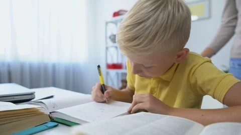 Diligent male kid doing homework at desk, mother praising son, touching head Vídeo Stock 118977376