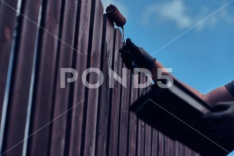 Diligent man is painting fence with brush Stock Photos